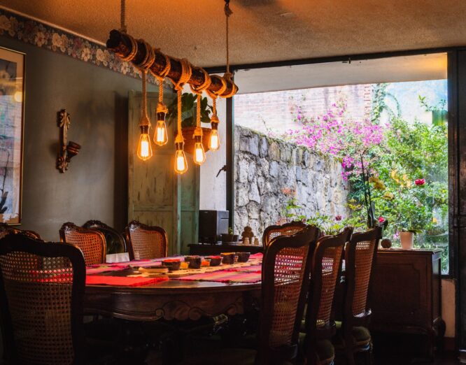 A rustic chandelier made of bulbs and ropes over a dining table in a vintage kitchen